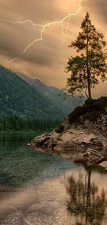 Lone tree by a lake with a dramatic lightning storm and mountains in the background.