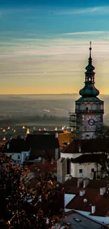 Scenic sunset over historic town rooftops and steeple.