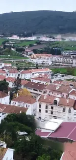 Aerial view of a town with hills and greenery in the background.