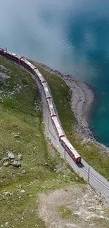 A red train navigating along a turquoise lake with lush green hills.