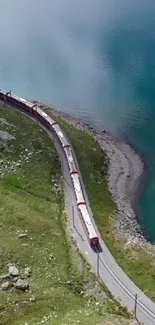 A scenic train winds beside a tranquil blue lake with lush green surroundings.