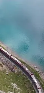 A train traveling alongside a stunning blue lake with a scenic natural backdrop.