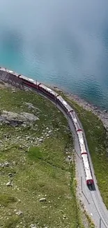 Aerial view of a red train beside turquoise waters and lush green landscape.