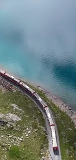 Scenic train travels by a teal lake and green landscape.