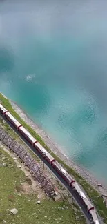 Scenic train travels by a turquoise lake.