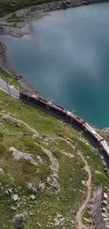 Red train on a scenic path by a turquoise lake.