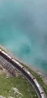 Train winds by a turquoise lake in a serene, scenic landscape.