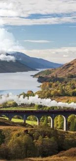 Train crossing a scenic viaduct with mountains and a valley in the background.