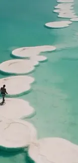 Person walking on salt formations in turquoise water.