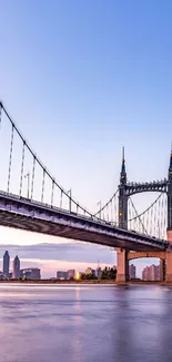 Scenic urban suspension bridge at twilight with city skyline.