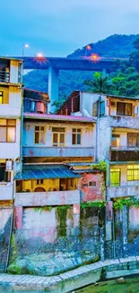 Scenic view of colorful urban buildings along a riverside under a sky blue bridge.