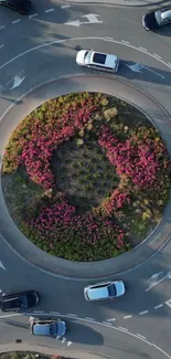 Aerial image of an urban roundabout with colorful flowers and moving cars.