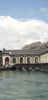 Urban waterway with historic building and cloudy sky.