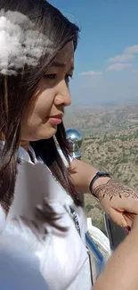 Woman with henna art against a cloudy sky.