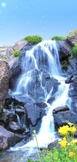 Scenic waterfall with vibrant flowers and lush greenery in a mountain setting.