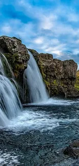 Scenic waterfall with blue sky and rocks, perfect for a tranquil mobile wallpaper.