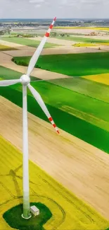 Bird's eye view of a wind turbine over colorful green fields.