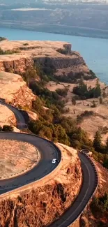 A stunning aerial view of cliffs and a winding road beside a river.