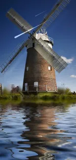 Scenic windmill with water reflection under clear blue sky.