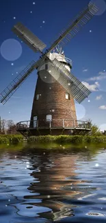 Windmill reflected in calm water under a clear blue sky.