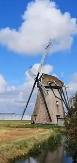 Traditional windmill under a blue sky with fluffy clouds, surrounded by fields.