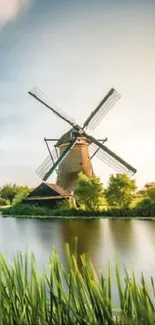 Serene riverside windmill at sunset with lush greenery.