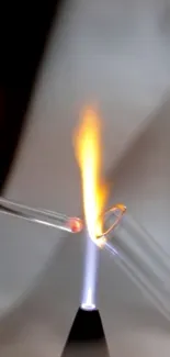 Two glass tubes meet over a flame, creating vibrant art.