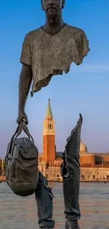 Modern sculpture with sunset sky and water in background.