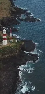 Aerial view of a lighthouse on a cliff by the ocean.