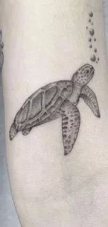 Minimalist sea turtle tattoo design on arm.