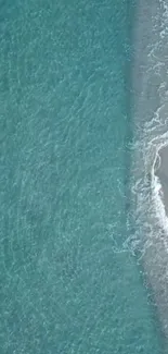 Aerial view of turquoise ocean waves meeting sandy beach.