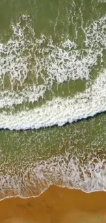 Aerial view of ocean waves meeting a sandy beach, creating a tranquil scene.