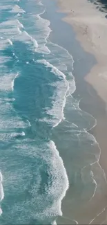 Aerial view of ocean waves meeting sandy beach.