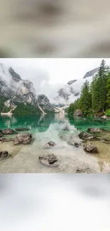 Serene alpine lake with misty mountains and green forest views.