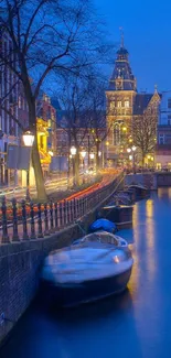 Tranquil Amsterdam canal at night with city lights reflecting on water.