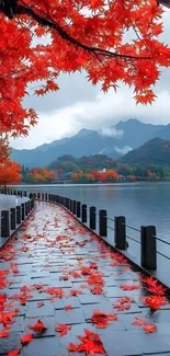 Serene scenic pathway with red autumn leaves by a lake under misty mountains.