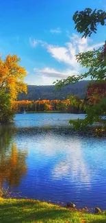 Serene lake with autumn trees and a clear blue sky.