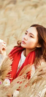 Girl in red scarf amidst golden grass field, serene autumn portrait.