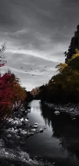 Serene autumn river with red foliage and distant mountains.