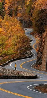 Winding road through vibrant autumn forest with orange foliage.