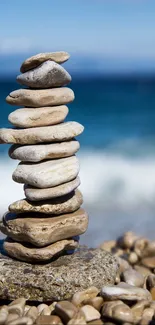 Peaceful coastal landscape with stacked stones and blue ocean waves.