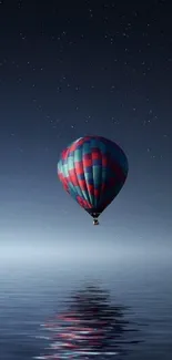 Colorful hot air balloon over calm water at night.