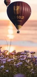 Hot air balloons float over a sunset with purple flowers in the foreground.