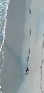 Aerial view of a serene sandy beach with turquoise waves hitting the shore.