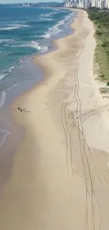 Aerial view of expansive beach with golden sand and blue ocean waves.