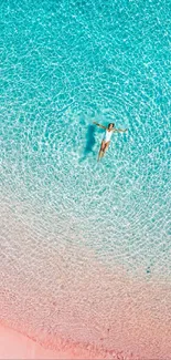 Aerial view of person floating on clear turquoise beach.