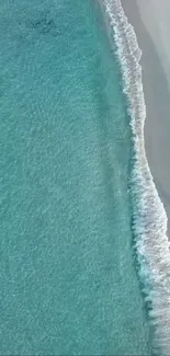 Aerial beach view with calm blue water and gentle waves along the shore.