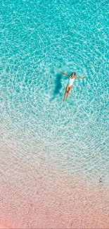 Aerial view of a person floating in tranquil turquoise ocean waters.