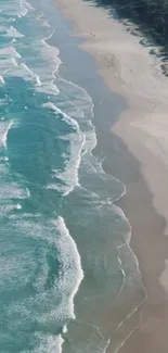 Aerial view of a turquoise ocean meeting a serene sandy beach.