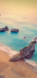 Beach at sunset with rocks and turquoise waters, perfect for mobile wallpaper.